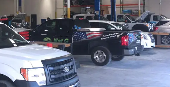 A truck is parked in the garage with other vehicles.